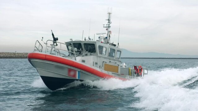 Slow motion footage of an American coast guard boat sailing near Los Angeles Harbor at sunset, USA