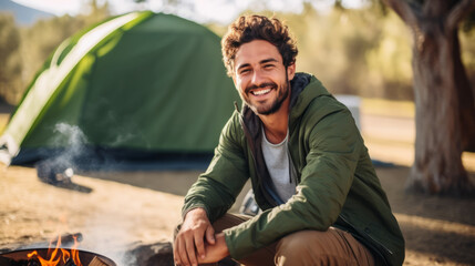 Portrait of happy captivating young man enjoying camping in a beautiful outdoor landscape with natural lighting