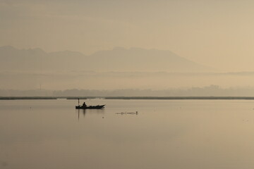 Obraz na płótnie Canvas Sunrise at Batu Jai Dam, Praya, Central Lombok. A fisherman is getting ready to catch fish