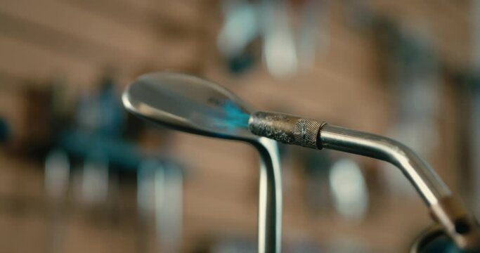 Flame torching a wedge in golf shop,wed club builder close up slow motion flames in 4k