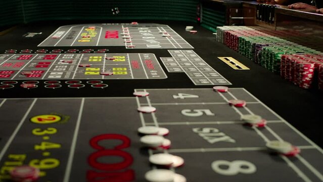 Closeup slow motion of a croupier hand throwing dices on dealing craps table in a casino club