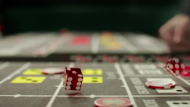 Closeup slow motion footage of a croupier hand throwing dices on dealing craps table in a casino