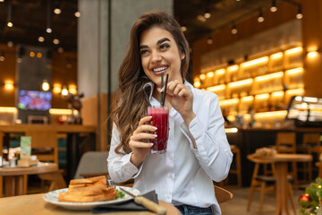 Cute young woman taking a smoothie break at a juice bar, Cheerful young woman having lunch and healthy smoothies at a juice bar