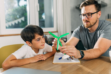 Father explaining mechanics on a windmill model to his son.