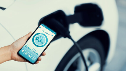 Smartphone display battery status on smart EV mobile application while EV car recharging...