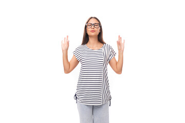 Fototapeta na wymiar A 30-year-old brunette model woman dressed in a striped T-shirt actively gesticulates towards the empty space