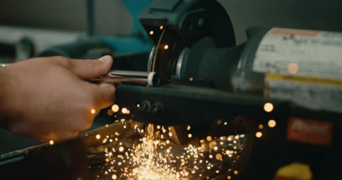 Golf club builder using saw to cut iron shaft in slow motion, sparks flying close up in 4k
