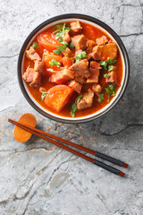 Asian Pork belly stewed with tomato, sweet soy sauce and spices close-up in a bowl on the table....
