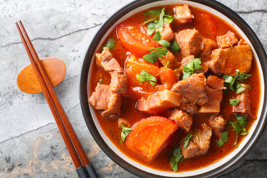 Spicy Pork Belly cooked with tomatoes, onions, sweet soy sauce and spices close-up in a bowl on the table. Horizontal top view from above