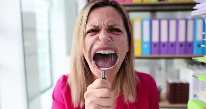 Angry woman screaming holding magnifying glass sitting working at table