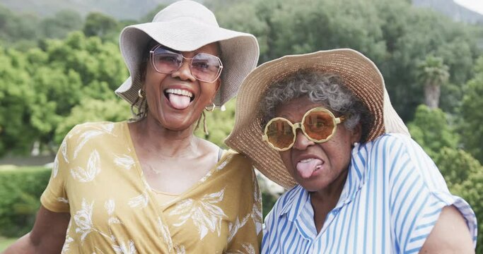 Portrait of happy senior african american female friends making funny faces in garden, slow motion