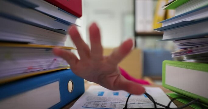 Working in office businesswoman looks through pile of paper files and reaches out hand