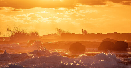 The view of a photographer taking pictures in tides and waves in Mooloolaba beach in the sunrise