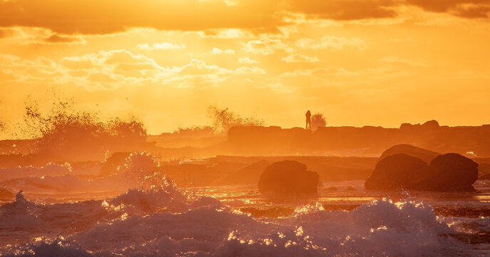 The view of a photographer taking pictures in tides and waves in Mooloolaba beach in the sunrise