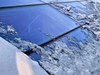 roof windows clogged with snow. roofing of greenhouse or atrium. snow is melting and coming down,...