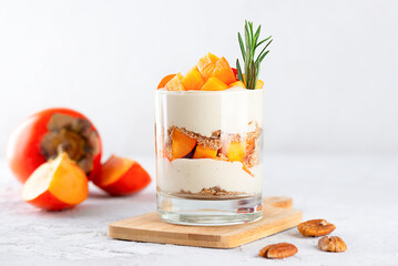 Trifle with persimmon, rosemary, pecan, whipped coconut cream and biscuit on a wooden board....