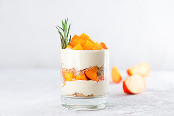 Dessert in a glass with persimmon, rosemary, pecan, whipped coconut cream. Healthy food, vegan,...