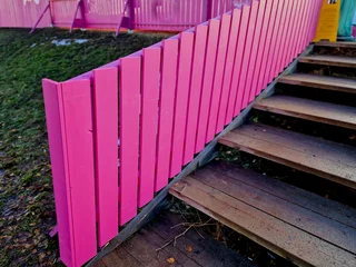 Foto op Canvas low fence, as protection against dogs. protects the playground from uninvited guests. The fence planks are made of recycled plastic and look almost like wood, wooden, steps, staircase © Michal