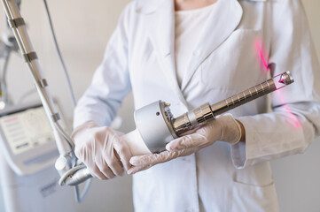 female doctor holds in hands carbon dioxide laser with phallic attachment for vaginal rejuvenation. Hardware cosmetology and medicine. Skin tightening, scar removal, stretch marks and lifting closeup - obrazy, fototapety, plakaty