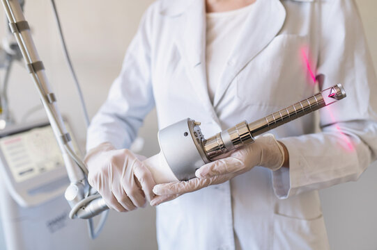 female doctor holds in hands carbon dioxide laser with phallic attachment for vaginal rejuvenation. Hardware cosmetology and medicine. Skin tightening, scar removal, stretch marks and lifting closeup