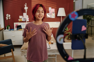 Happy teenage girl with perforation lines on her face making livestream from ward of plastic...