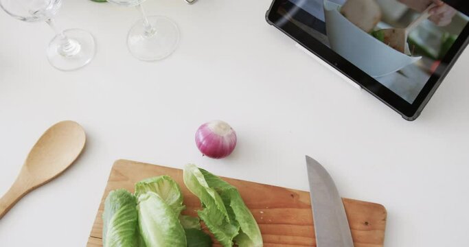 Vegetables, cheese, knife, chopping board and tablet on kitchen worktop, copy space, slow motion