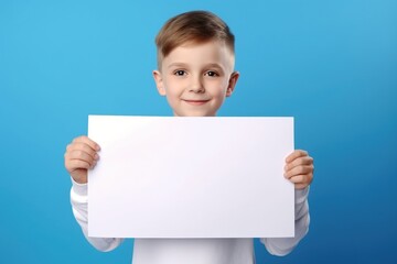 Fototapeta premium Little boy holding a blank white sheet of paper