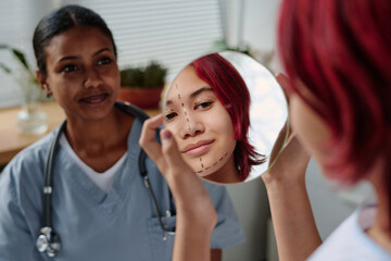 Reflection in round mirror of cute teenage girl with liftmarks on her face preparing for cosmetic procedure or plastic surgery in clinics - obrazy, fototapety, plakaty
