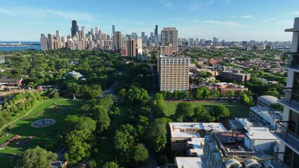 Chicago skyline as seen from Lincoln Park during summer. Aerial view of green space in urban USA cityscape. Fly past apartment skyscraper.