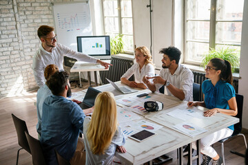Group of young confident happy business people analyzing data during meeting in the office