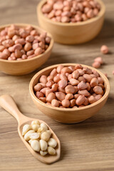 Peanut in bowl with spoon on wooden background