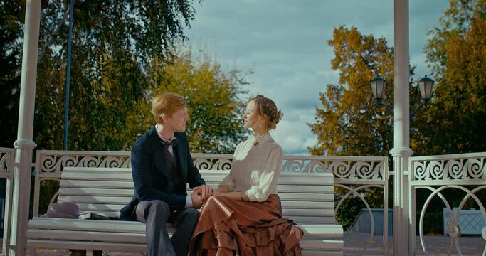 history of 19th century, Caucasian man and woman sitting on bench in park and laughing, 4K, Prores