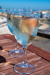 Drinking of white wine at farm cafe in oyster-farming village, with view on boats and water of Arcachon bay, Cap Ferret peninsula, Bordeaux, France