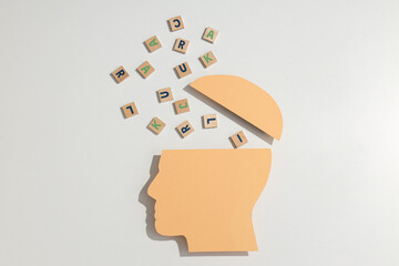 Paper model of human head with wooden letters