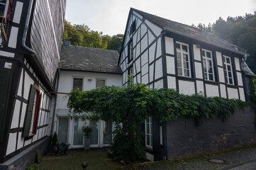 View of houses and streets of old colourful German town Monschau in bend of the river and hidden between the hills, Eifel national park, Germany