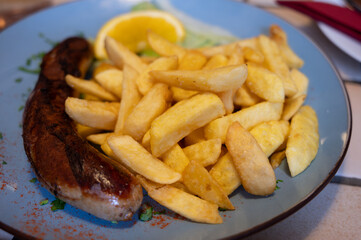 Fried fries potatoes with grilled meat German sausage served in old restaurant in Germany
