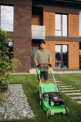 Man in his sunny garden mowing the grass with a lawn mower