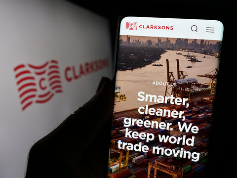 Stuttgart, Germany - 12-06-2023: Person holding cellphone with webpage of British logistics company Clarkson plc (Clarksons) in front of logo. Focus on center of phone display.