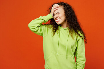 Young sad woman of African American ethnicity she wear green hoody casual clothes put hand on face...