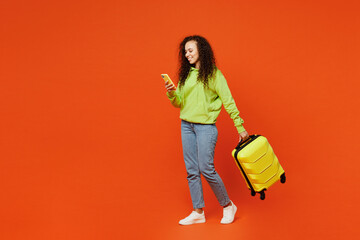 Full body traveler woman wears casual clothes hold bag use mobile cell phone isolated on plain orange background. Tourist travel abroad in free spare time rest getaway Air flight trip journey concept