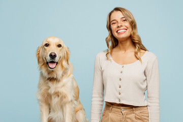 Young smiling happy cheerful owner woman with her best friend retriever dog she wear casual clothes looking camera isolated on plain pastel light blue background studio. Take care about pet concept.
