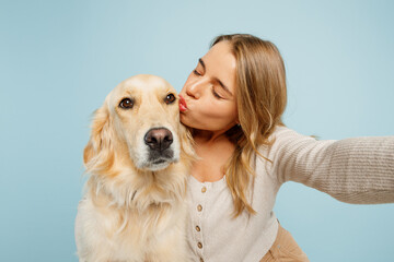 Close up young owner woman with her best friend retriever wear casual clothes do selfie shot on mobile cell phone kiss dog isolated on plain pastel light blue background. Take care about pet concept.
