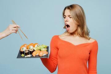 Young indignant sad displeased woman wear orange casual clothes hold eat do want to share wit...