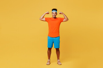 Full body young happy fitness trainer sporty man sportsman wear orange t-shirt show muscles biceps...