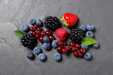 Many different fresh ripe berries on dark grey table, flat lay