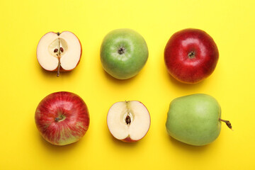 Whole and cut colorful apples on yellow background, flat lay