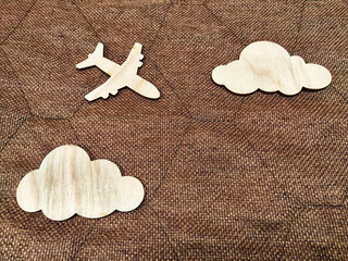 Fototapeta na wymiar Wooden toy airplane and clouds on a brown background. The concept of traveling by plane. Tourism, travel, speed. Takeoff, landing. The crash in storm