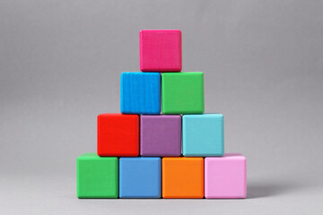 Pyramid of blank colorful wooden cubes on light grey background