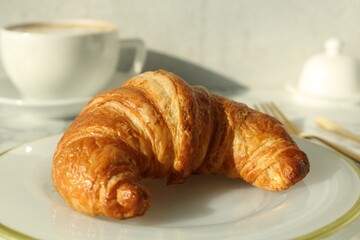 Plate with delicious fresh croissant on table, closeup