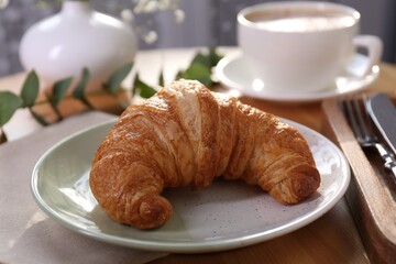 Tasty croissant served on wooden table, closeup